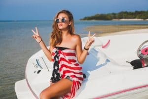 heureuse-femme-enveloppee-dans-drapeau-americain-vacances-tropicales-ete-voyageant-bateau-mer-fete-plage-gens-s-amusant-ensemble-emotions-positives